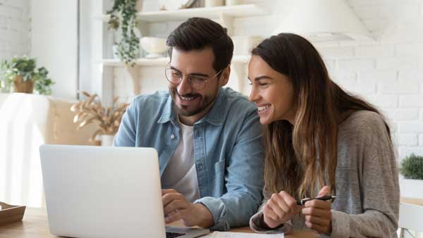 Couple sitting in front of laptop smiling