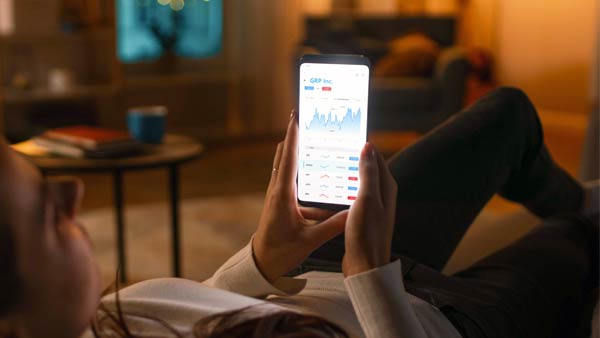 person on a couch with mobile phone looking at financial graphs - diy investing vs financial advice